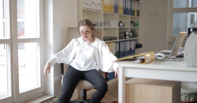 Behavior - Bossy female employee in formal wear sitting on chair in workplace and demonstrating frivolous and unprofessional behavior while looking away