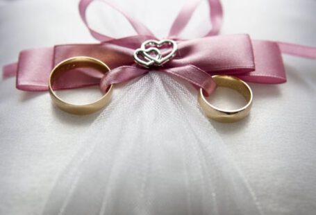 Engagement - Selective Focus Photography of Silver-colored Engagement Ring Set With Pink Bow Accent on Throw Pillow